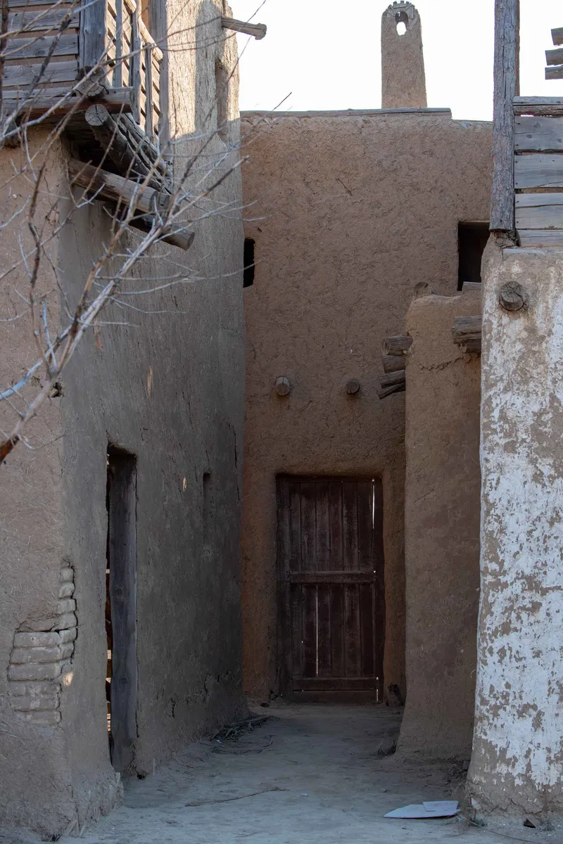 Narrow alley between mud-brick buildings with a wooden door at a nomad movie set